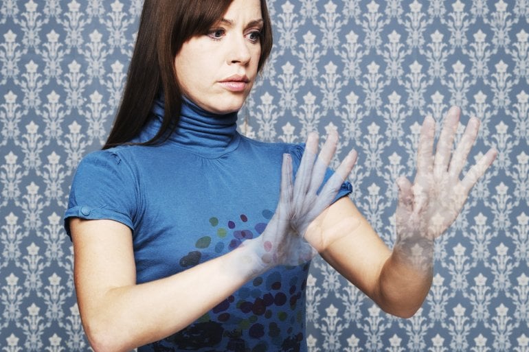 Frau mit Halluzinationen betrachtet verwirrt ihre transparent werdenden Hände