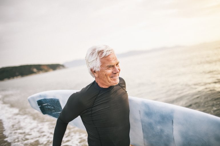 Älterer Mann mit Surfbrett