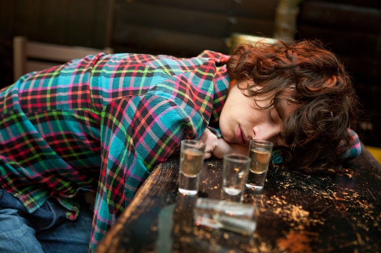 Junger Mann mit Alkoholvergiftung schläft auf Tresen