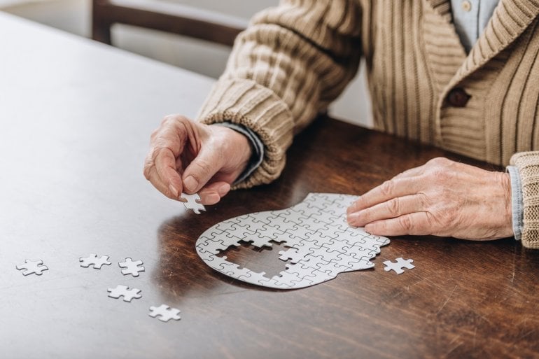 Mann mit Alzheimer bei Puzzle (menschlicher Kopf)