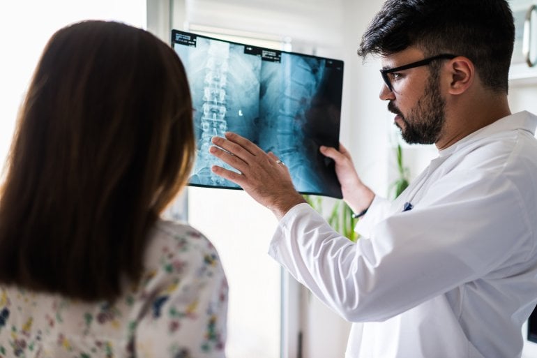 Arzt zeigt Patientin Röntgenbild eines Bandscheibenvorfalls