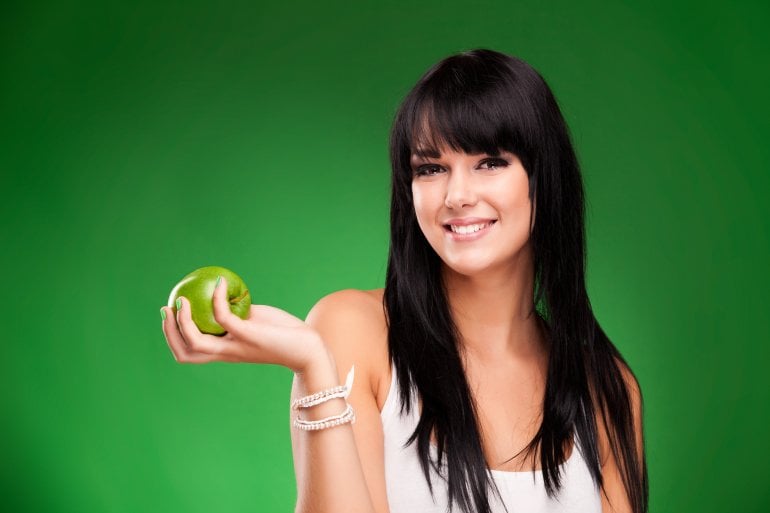 Frau isst Apfel, um Blutzucker zu senken