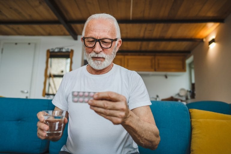 älterer Mann hält Packung Clopidogrel-Tabletten