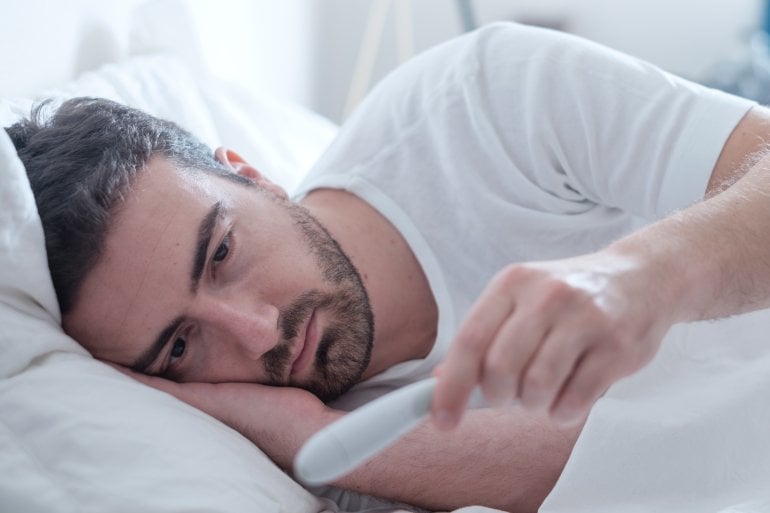 Mann mit grippalem Effekt im Bett