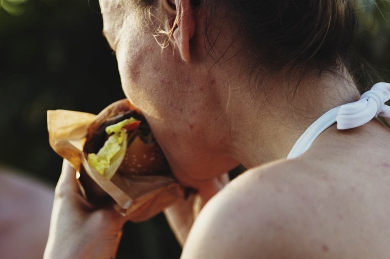 Frau mit Esssucht (Binge Eating Disorder) beißt in Burger