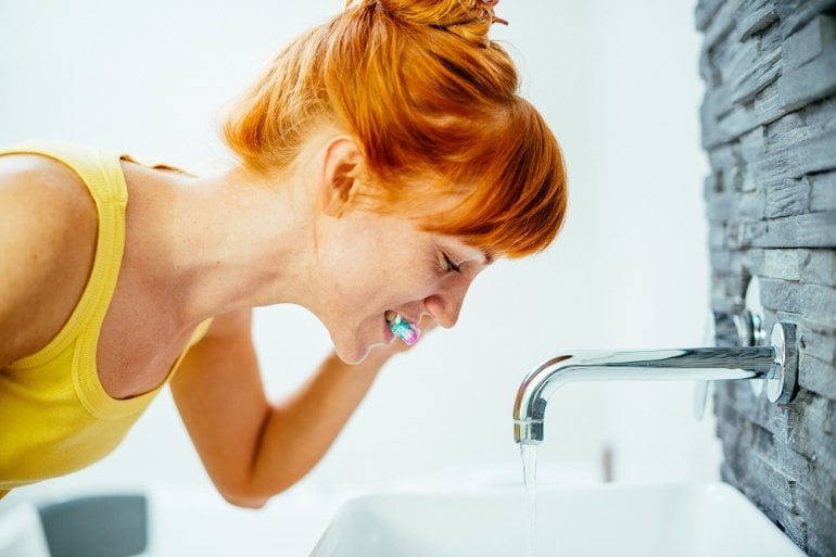 Frau putzt Zähne mit fluoridhaltiger Zahnpasta
