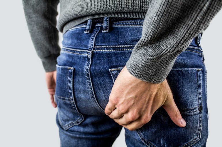 Mann mit Hämorrhoiden greift sich an Gesäß