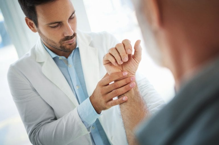 Arzt untersucht Mann mit Schmerzen im Handgelenk