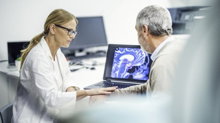 Ärztin zeigt Mann mit Hirntumor sein Kopf-MRT