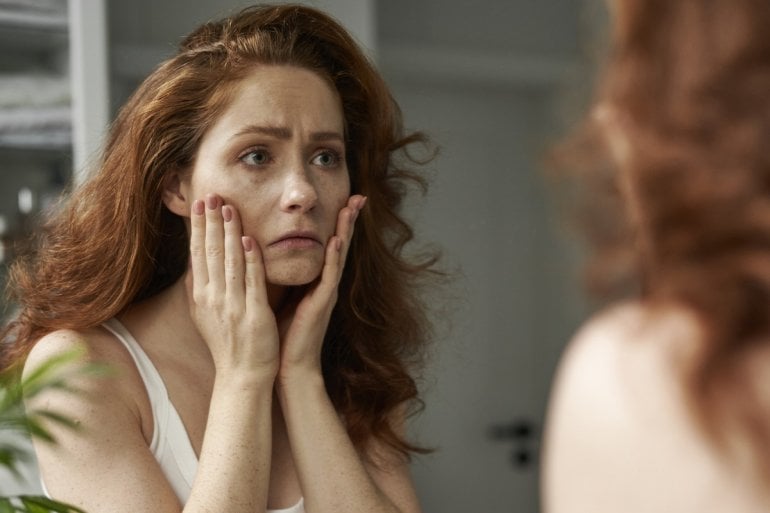 Frau mit hypochondrischer Störung betrachtet sich im Spiegel