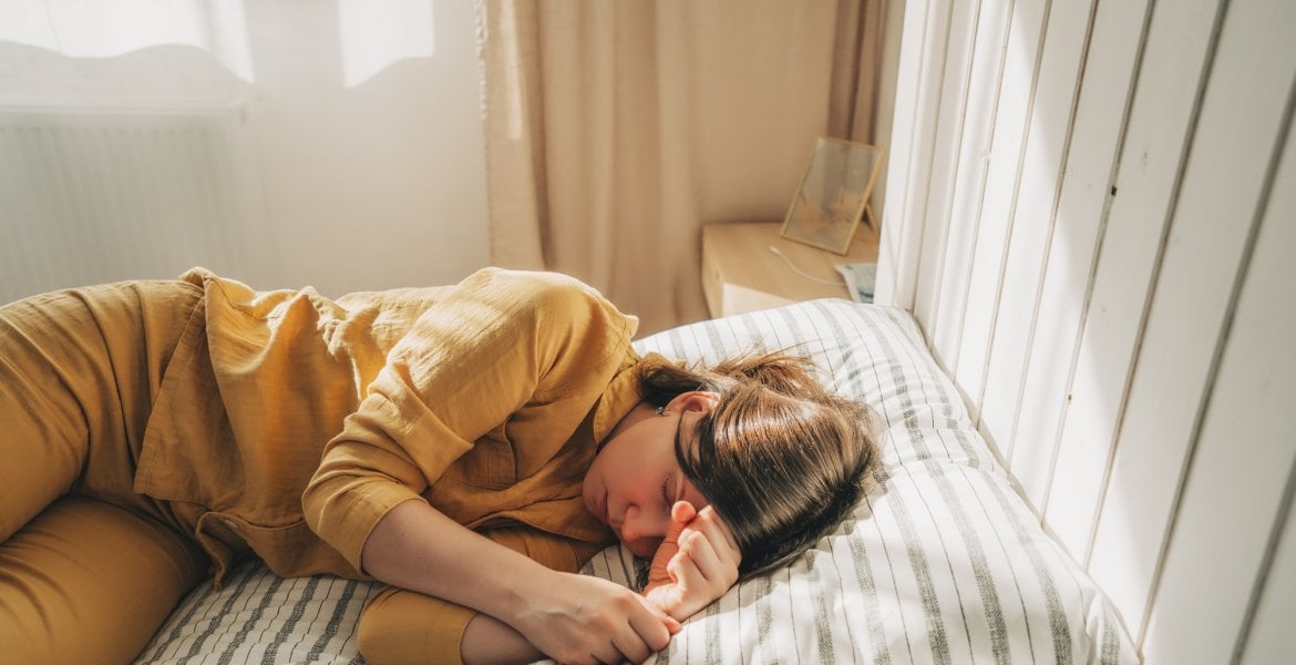 Frau mit ME/CFS liegt auf ihrem Bett