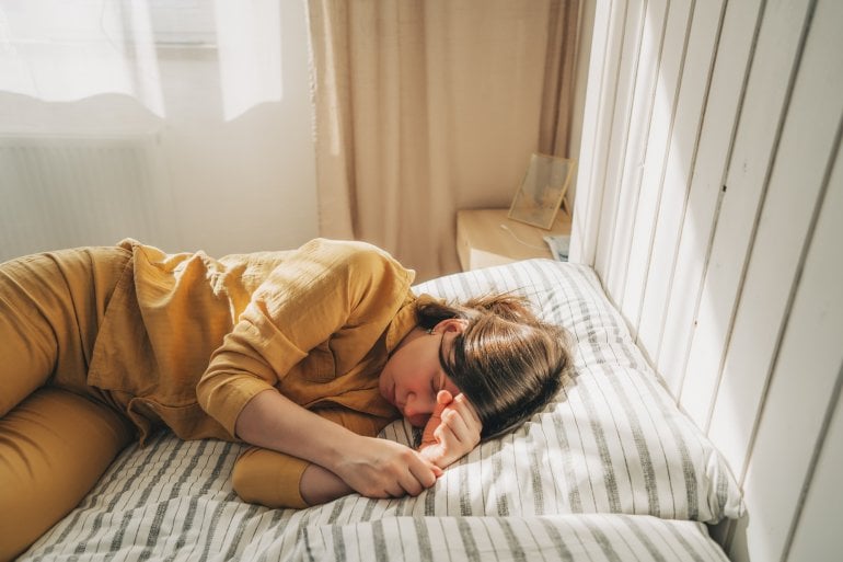 Frau mit ME/CFS liegt auf ihrem Bett