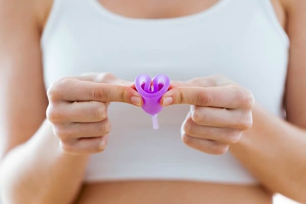 Frau faltet eine Menstruationstasse