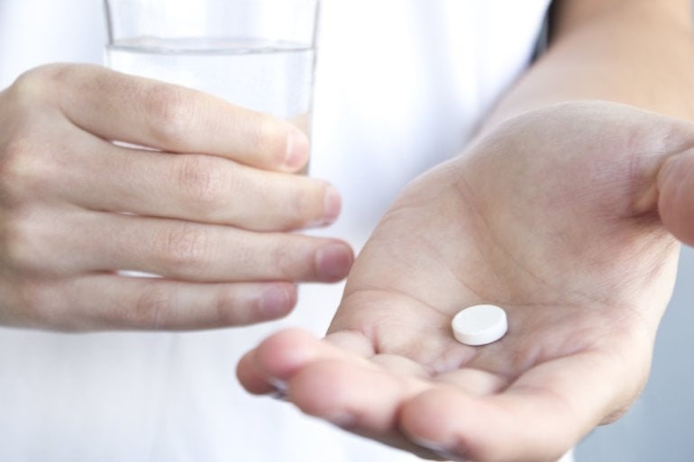 Hand hält eine Methadon-Tablette