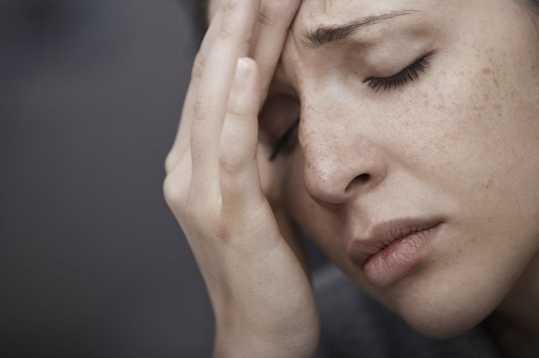 Frau mit Migräne greift sich an Kopf