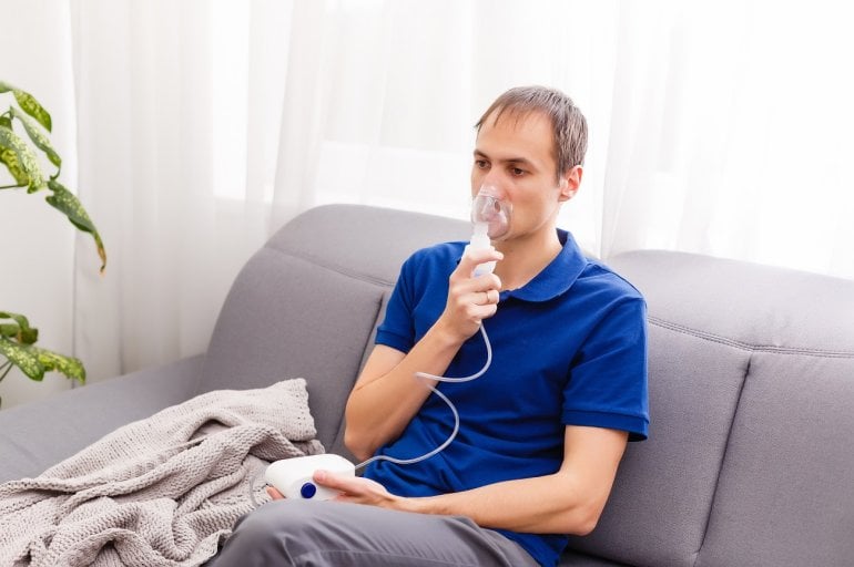 Mann mit Mukoviszidose an Inhalationsgerät