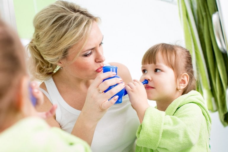 Frau hält Nasendusche an Nase ihres Kindes