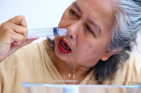 Frau zeigt Anwendung einer Nasenspülung