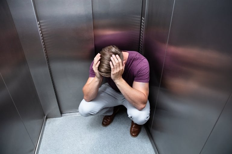 Mann mit Panikattacke im Aufzug