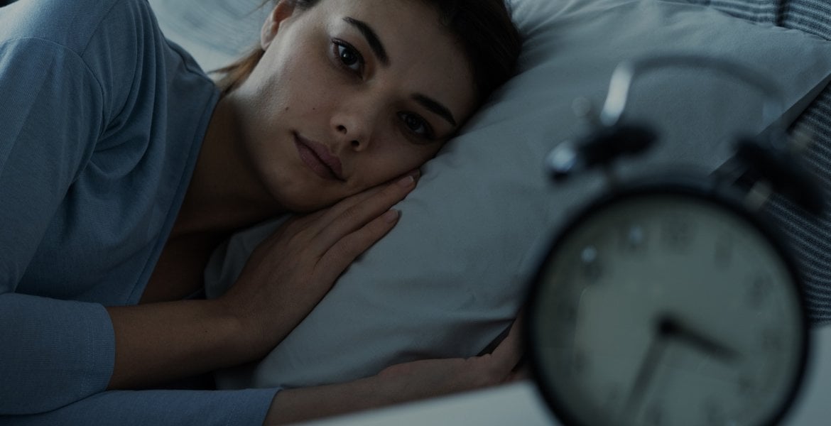 Frau mit Schlafstörungen liegt wach im Bett