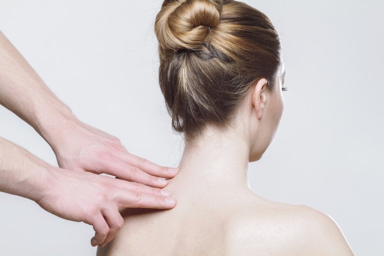 Hände massieren Frau mit Schulterschmerzen