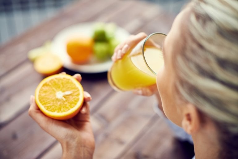 Frau trinkt Orangensaft zur Stärkung des Immunsystems