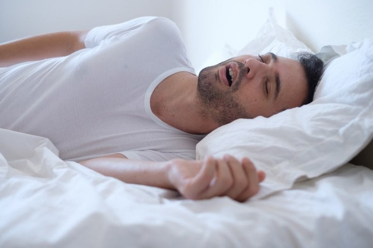 Mann mit obstruktiver Schlafapnoe liegt im Bett