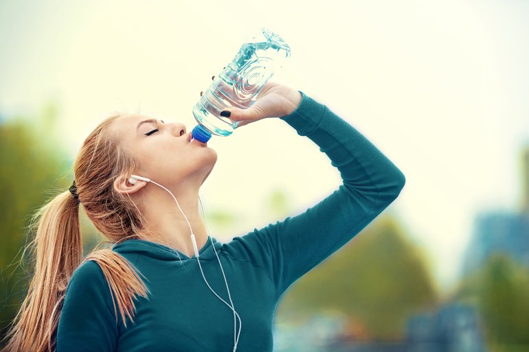 Frau trinkt Wasser an heißem Sommertag