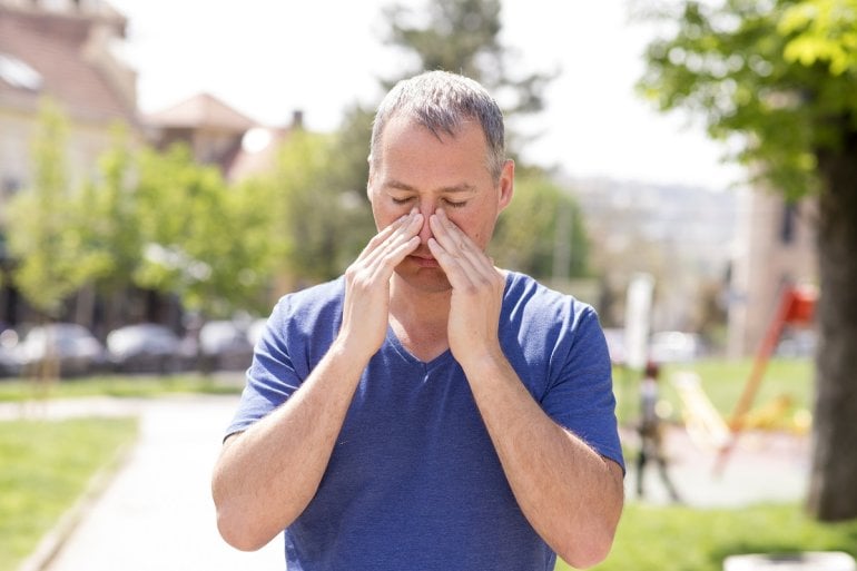 Mann mit trockener Nasenschleimhaut berührt Nase