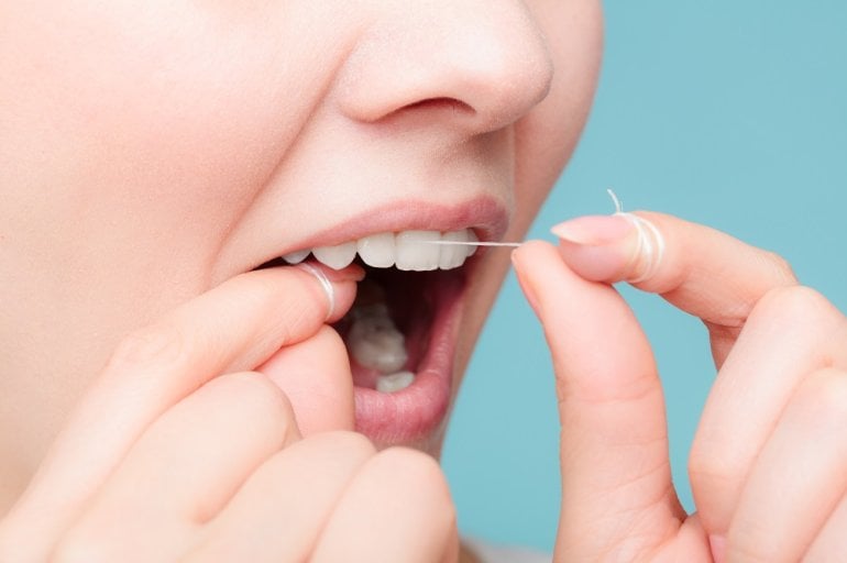 Frau verwendet Zahnseide zur Zahnpflege