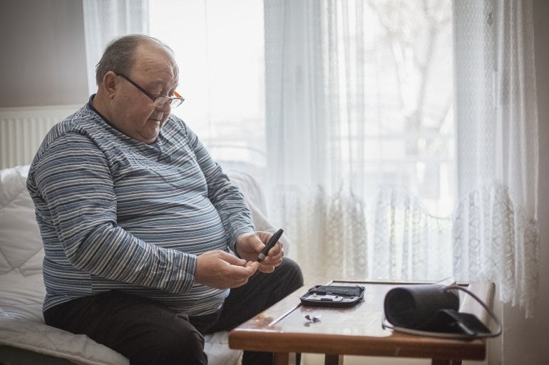 übergewichtiger Mann mit metabolischem Syndrom misst Blutzucker und Blutdruck