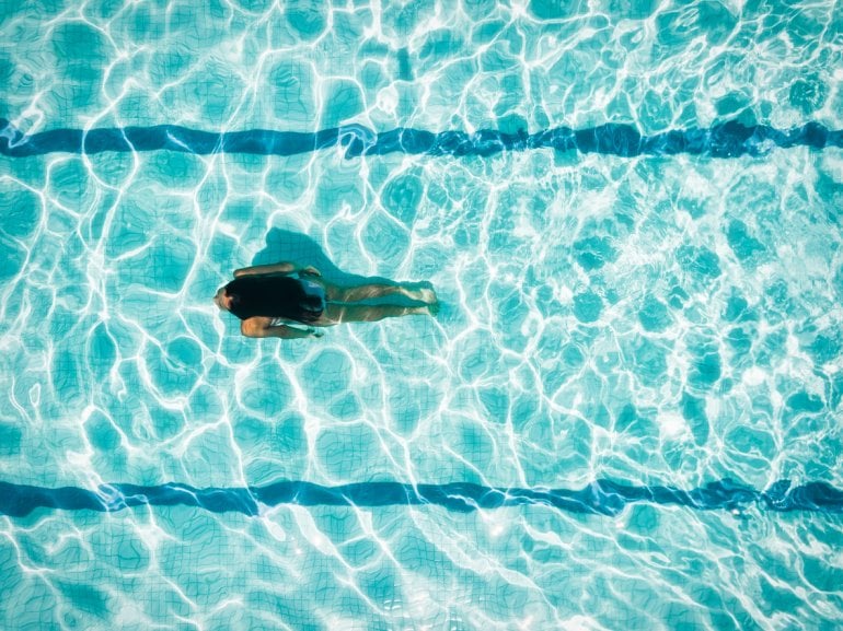 Frau schwimmt im Schwimmbad in Corona-Zeit